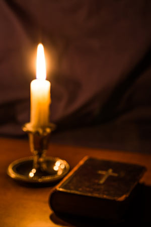 Candle Burning Next to Bible